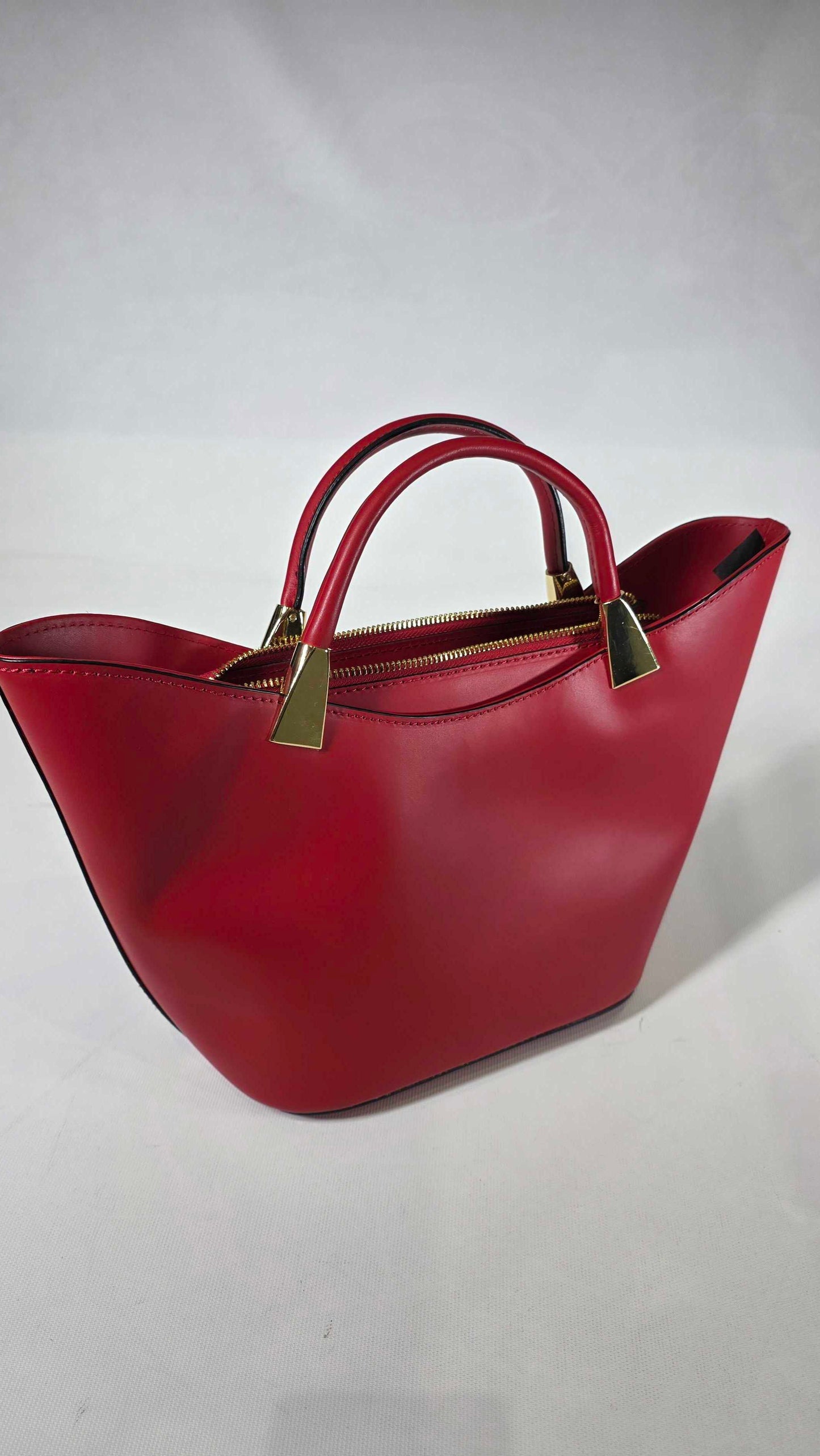 Red handbag with gold handles on a light gray background